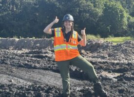 Woman smiling and thumbs-upping standing in mud